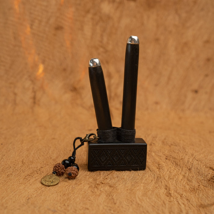 Black incense holder with two sticks on a wooden surface