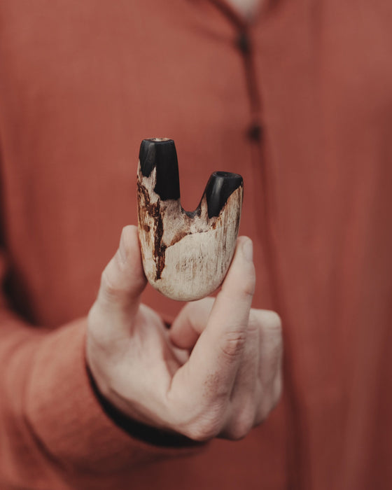 Person holding a wooden tool with black accents, wearing a brown jacket.