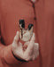 Person holding a wooden tool with black accents, wearing a brown jacket.
