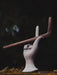 Wooden sculpture of a hand holding a stick against a dark background