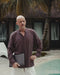 Man holding a laptop by a pool with palm trees and a building in the background
