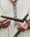Person holding a dark wooden tool with a blurred background