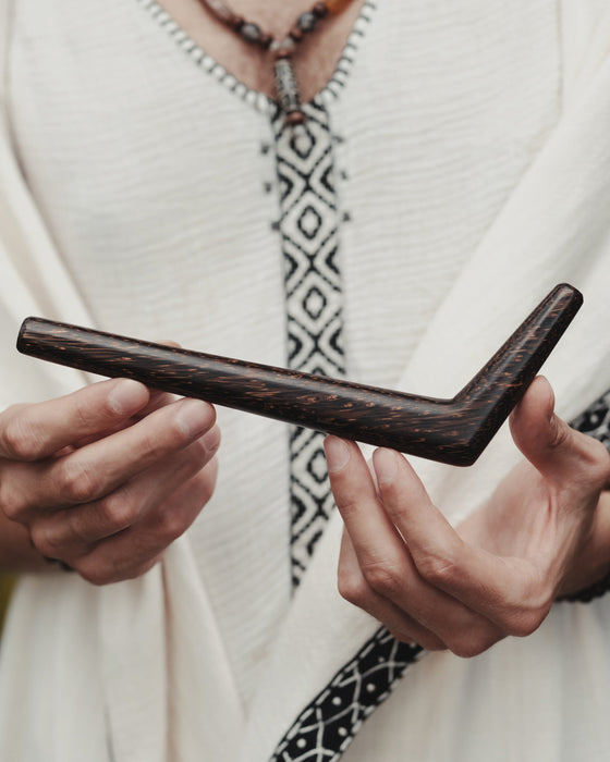 Person holding a dark wooden tool with a blurred background