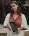 Woman holding a decorative box with intricate designs outdoors