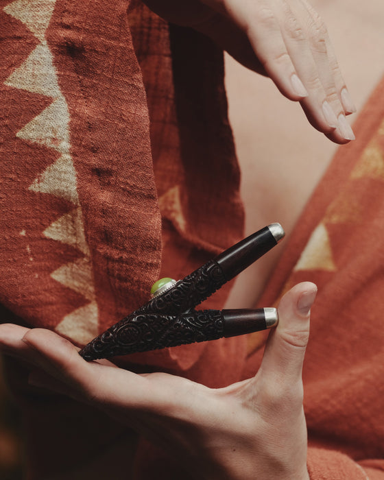 Person holding a black textured object against a warm-toned fabric background
