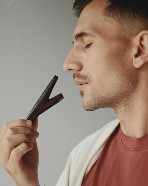 Man holding a black hair clipper against his face on a gray background