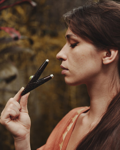 Woman holding a black object close to her face with a blurred natural background