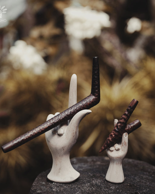 Decorative ceramic hands holding wands with a blurred natural background