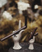 Decorative ceramic hands holding wands with a blurred natural background