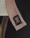 Close-up of a brown belt with a logo on a black garment, featuring the AYAGO brand.