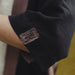 Close-up of a dark fabric with an embroidered logo on a blurred background