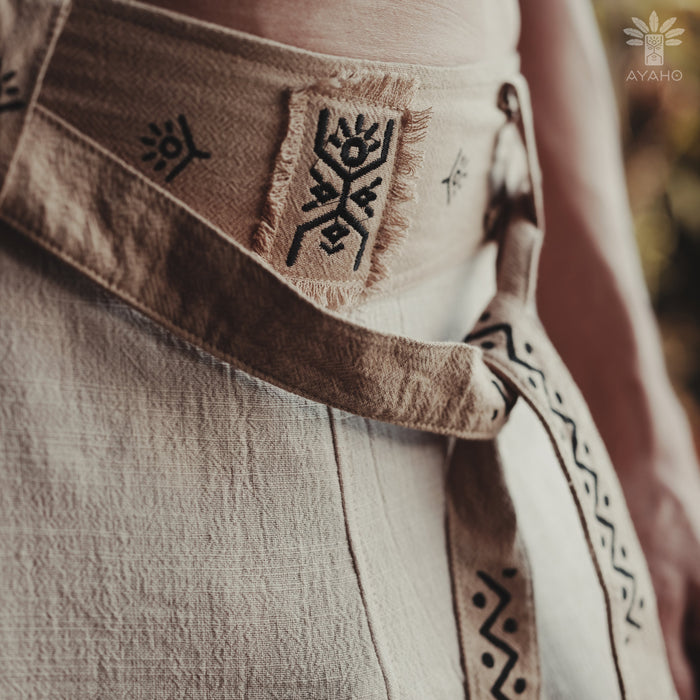 Close-up of a textured fabric with embroidered patterns and a brand logo in the corner.