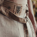 Close-up of a textured fabric with embroidered patterns and a brand logo in the corner.