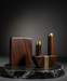 Wooden and brass decorative items on a dark marble base against a dark background
