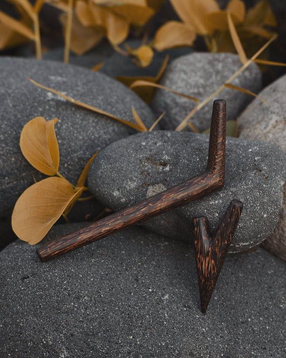 Wooden tool with a pointed end on a rocky surface with leaves