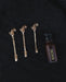 Three gold hair sticks with horse designs and a small bottle labeled 'INLAN' on a dark background.