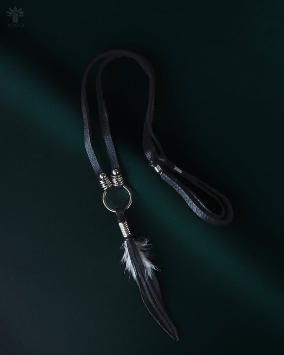 Black raven feather encased in resin with silver wire wrapping, hanging from a black leather choker for an edgy spiritual look