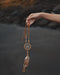 Close-up of a traditional-style dream catcher amulet with amethyst and howlite beadsx, hanging from a car mirror.