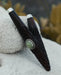 Decorative pen with intricate design and green stone on a textured surface