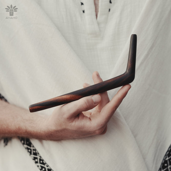 Hand holding a wooden tool with a blurred white background