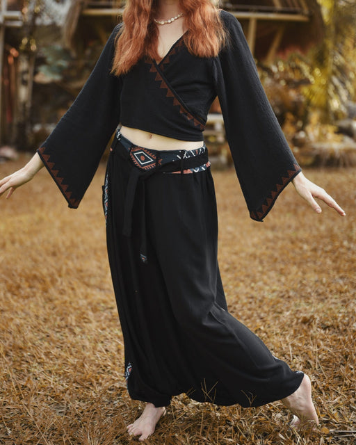 Person wearing a black outfit with decorative elements in an outdoor setting