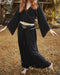 Person wearing a black outfit with decorative elements in an outdoor setting