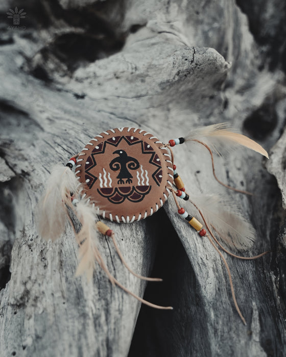 Handcrafted eagle feather brooch with painted details, symbolizing earth energy and spiritual transition, pinned to a tribal-printed shawl