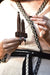 Person holding a small wooden tool with beads against a patterned background