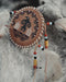 Handcrafted eagle feather brooch with painted details, symbolizing earth energy and spiritual transition, pinned to a tribal-printed shawl