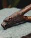 Wooden walking stick with bear head carvings on a stone surface