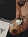 Gold pendant on a wooden surface with a branded bag in the background