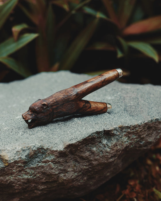 Wooden bear figurine on a stone surface with blurred greenery in the background