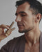 Man holding a leopard-print object near his face against a neutral background