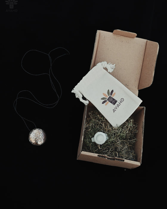 Necklace with pendant, small bag, and decorative stones in a cardboard box on a black background
