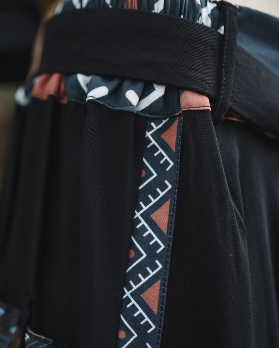 Close-up of a black garment with a patterned strap featuring triangles and lines.