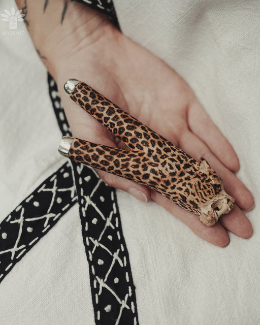Hand holding a leopard print object with a blurred background