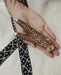 Hand holding a leopard print object with a blurred background
