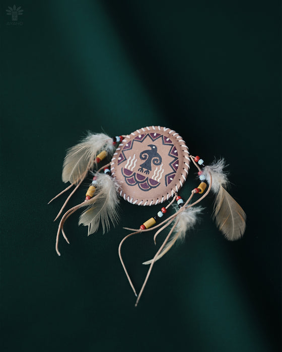 Handcrafted eagle feather brooch with painted details, symbolizing earth energy and spiritual transition, pinned to a tribal-printed shawl