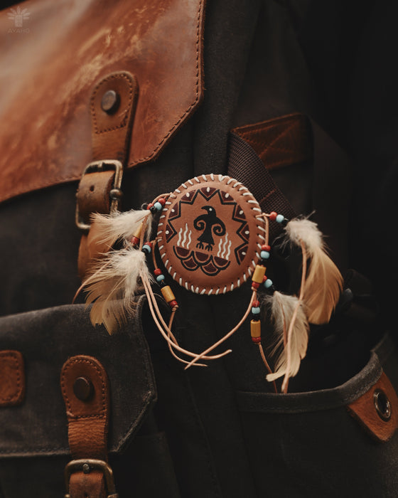 Handcrafted eagle feather brooch with painted details, symbolizing earth energy and spiritual transition, pinned to a tribal-printed shawl