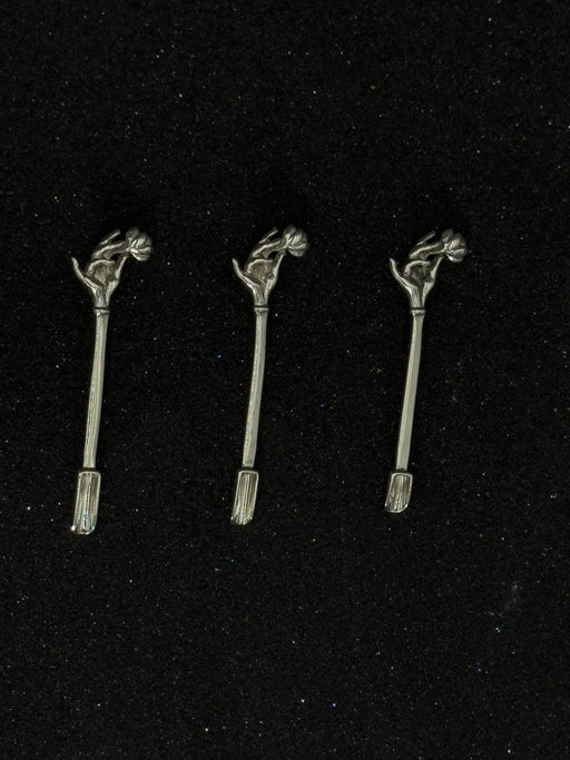 Three metallic hair accessories with decorative elements on a black background