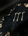 Three silver hairpins on a textured black surface with a patterned fabric background.