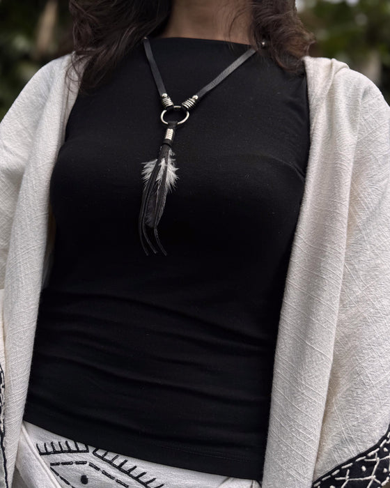 Black raven feather encased in resin with silver wire wrapping, hanging from a black leather choker for an edgy spiritual look