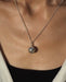 Detailed view of a handcrafted silver harmony bell pendant, serving as a talisman amulet, associated with heart healing and negative energy protection