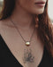Personalized copper pendant with initials carved near the mirror, laid on handmade paper with ink-dyed fabric.