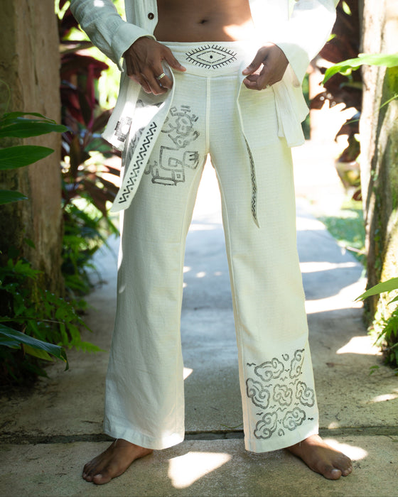 Person wearing white pants with intricate designs outdoors