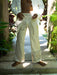 Person wearing white embroidered pants and shirt in a tropical setting