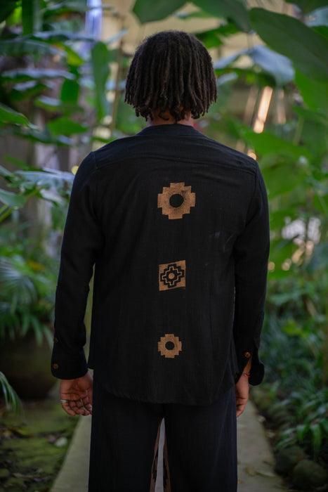 Person wearing a black jacket with geometric patterns in a forest setting