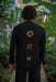 Person wearing a black jacket with geometric patterns in a forest setting