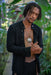 Man with dreadlocks wearing a black shirt in a tropical setting