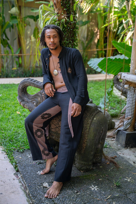 Man sitting on a stone bench outdoors with greenery in the background